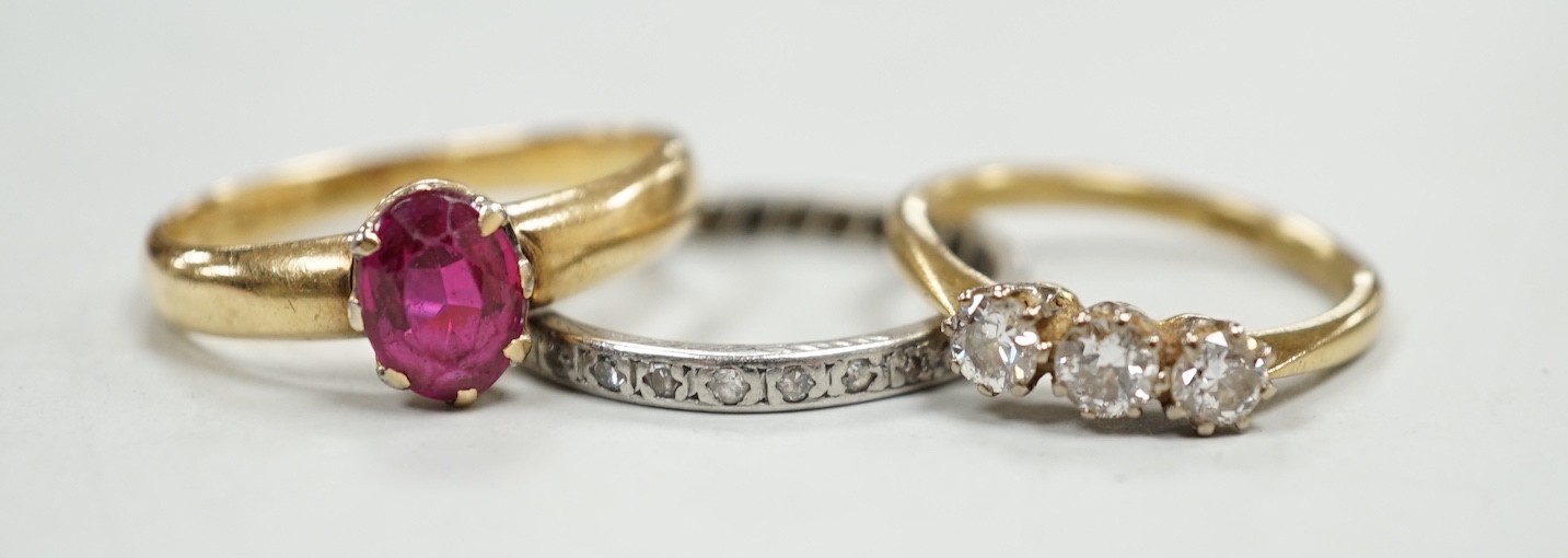 An 18ct and solitaire synthetic? ruby set ring, an 18ct and three stone diamond ring and a white metal and diamond chip set full eternity ring, gross weight 10.9 grams.